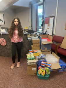 Alicianna Bersani, founder of "The Dominick Foundation- SIDS Siblings Survivors" stands next to boxes of supplies gathered to be given to kindergarten students in the school district.
